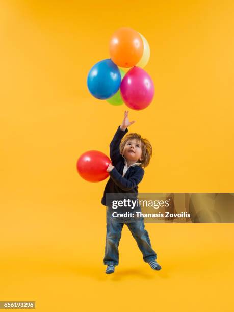 portrait of a 2 year old boy over yellow background - child balloon studio photos et images de collection