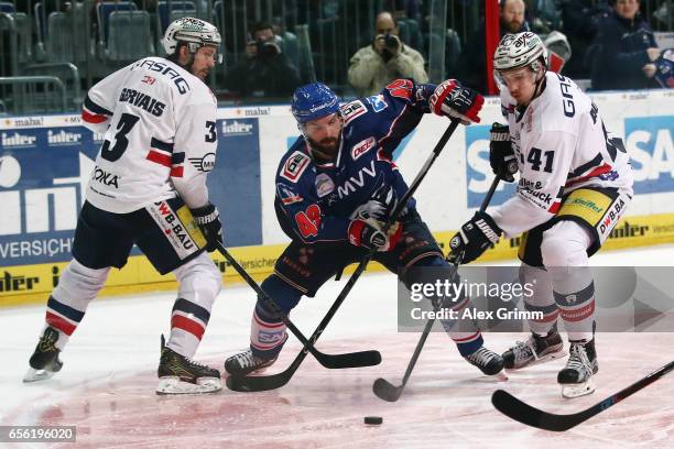 Jamie Tardif 8c9 of Mannheim is challenged by Bruno Gervais and Louis-Marc Aubry of Berlin during the DEL Playoffs quarter finals Game 7 between...