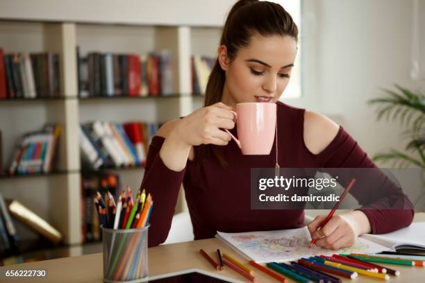 young woman relaxing at home by coloring book - adult coloring stock pictures, royalty-free photos & images