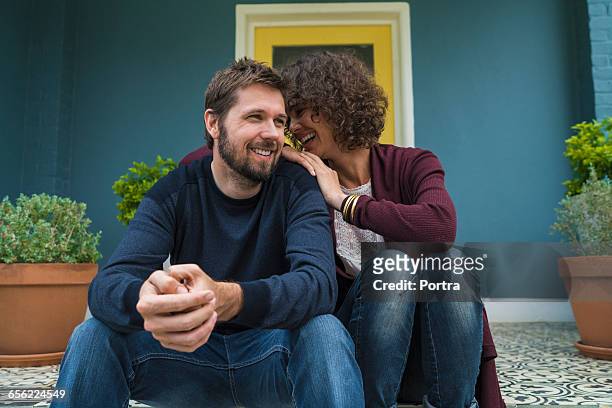 woman laughing with spouse while sitting on porch - serene people stock pictures, royalty-free photos & images