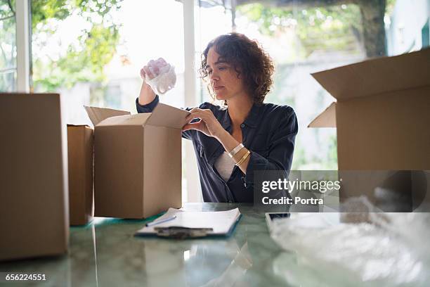 woman paking coffee cup in cardboard box at home - wrap blouse stock pictures, royalty-free photos & images