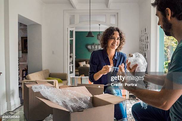 happy woman with spouse packing cardboard boxes - packing boxes stockfoto's en -beelden