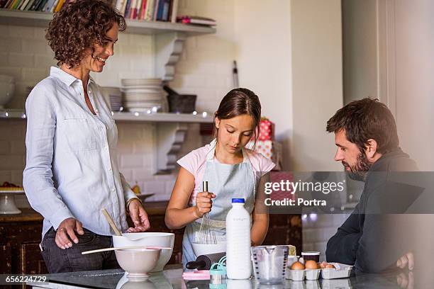 parents looking at girl baking in kitchen at home - women whipping men 個照片及圖片檔