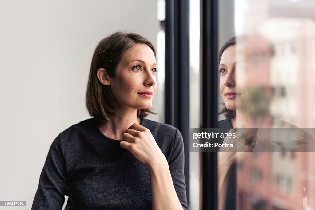 Thoughtful businesswoman looking through window