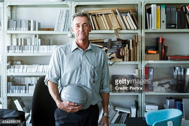 mature businessman holding hardhat in workshop - portrait man building stock pictures, royalty-free photos & images
