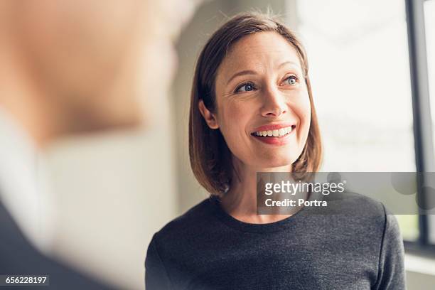 smiling female architect looking away in office - looking away stock-fotos und bilder