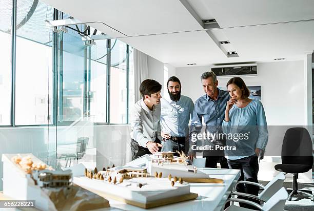 team of architects examining model in board room - architectural model stockfoto's en -beelden