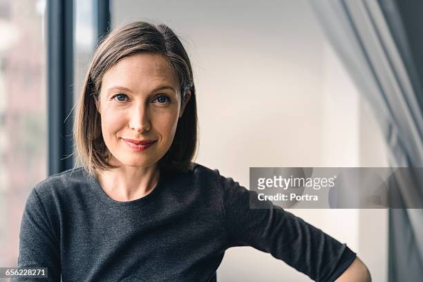 confident businesswoman smiling in office - in den dreißigern stock-fotos und bilder