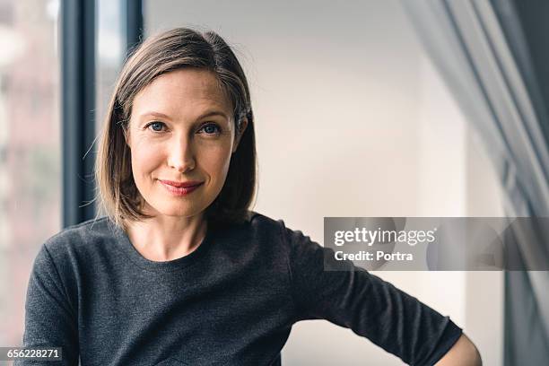 confident businesswoman smiling in office - business mid adult woman stock pictures, royalty-free photos & images