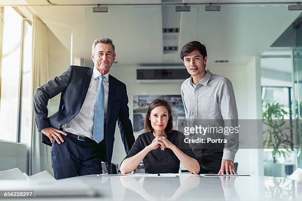 portrait of confident business people at desk - dreier stock-fotos und bilder
