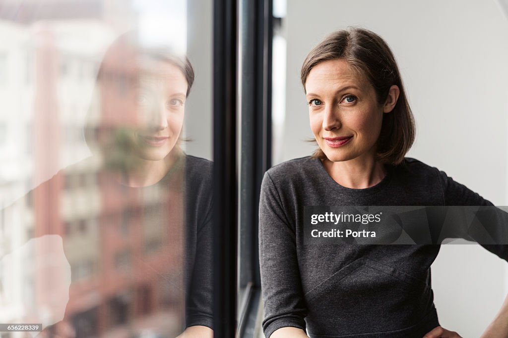 Confident businesswoman standing by window