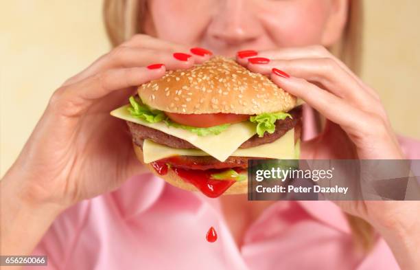 woman biting into hamburger with ketchup drip - hand holding burger stock pictures, royalty-free photos & images