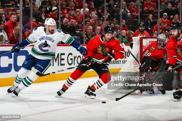 Jack Skille of the Vancouver Canucks and Nick Schmaltz of the Chicago Blackhawks skate around the net, as Brent Seabrook approaches from the right,...