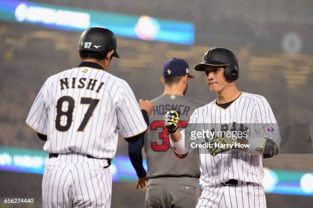 Seiji Kobayashi celebrates a single with coach Toshihisa Nishi in the third inning against team United States during Game 2 of the Championship Round...