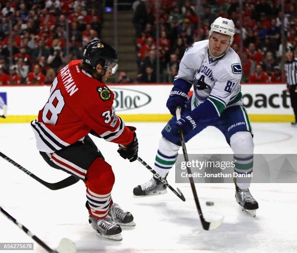 Ryan Hartman of the Chicago Blackhawks shoots the puck between the legs of Nikita Tryamkin of the Vancouver Canucks at the United Center on March 21,...