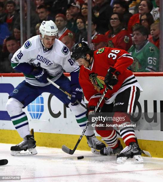 Ryan Hartman of the Chicago Blackhawks tries to control the puck under pressure from Nikita Tryamkin of the Vancouver Canucks at the United Center on...