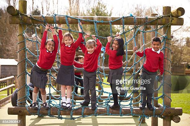 elementary school pupils play on climbing frame at breaktime - climbing frame stockfoto's en -beelden