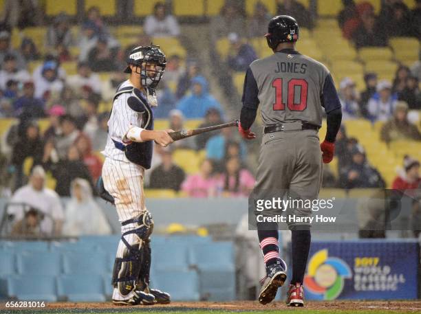 Catcher Seiji Kobayashi of team Japan hands the bat back to Adam Jones of team United States in the fourth inning during Game 2 of the Championship...