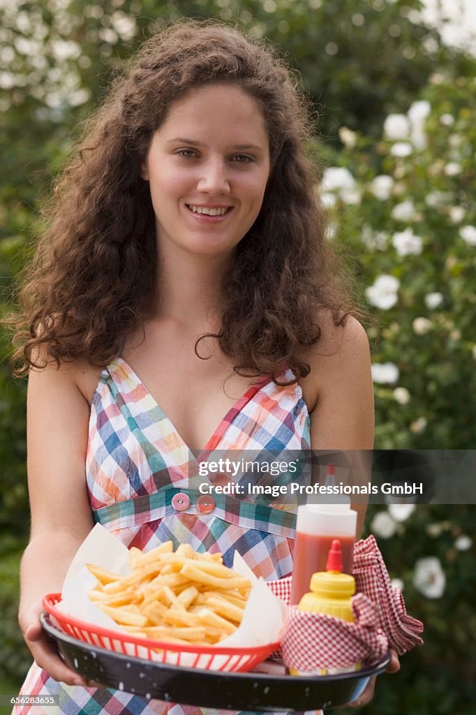 Woman holding tray of chips, ketchup and mustard