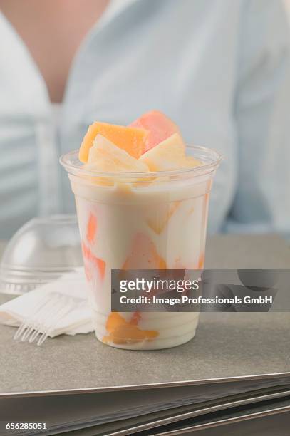 fruit yoghurt in office, woman in background - yoghurt pot stock pictures, royalty-free photos & images