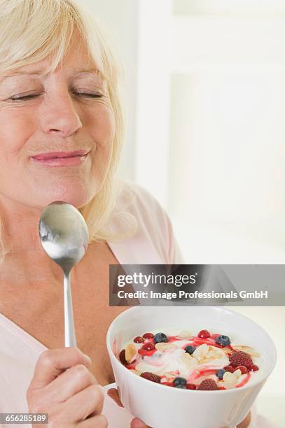 woman enjoying yoghurt with berries and flaked almonds - almond joy stock pictures, royalty-free photos & images