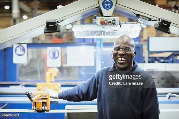 Portrait smiling worker at machine in steel factory