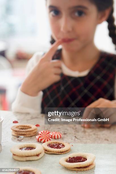 girl sucking jam from her finger while making biscuits - jam making generations photos et images de collection