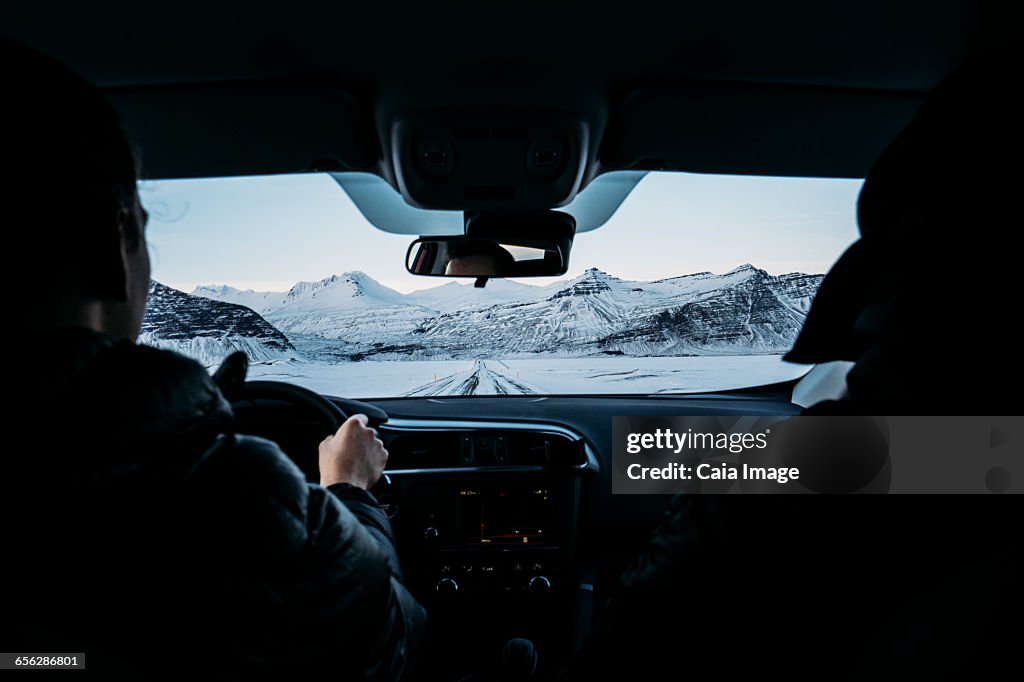 Men driving car through snow covered landscape, Iceland