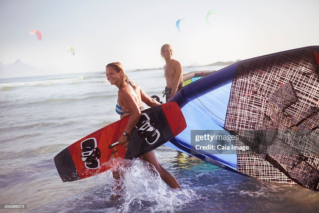 Couple pulling kiteboarding equipment into ocean surf