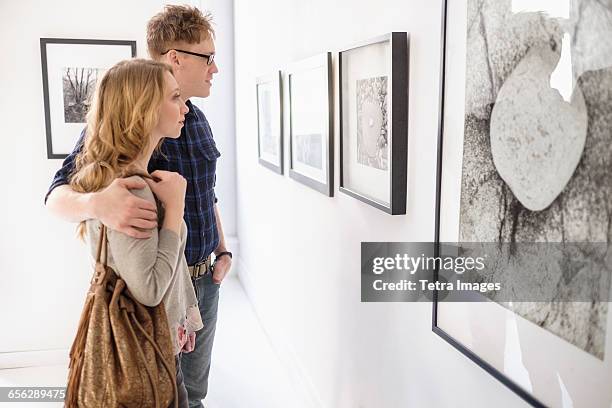 young couple looking at photographs at museum - couple art gallery stock pictures, royalty-free photos & images