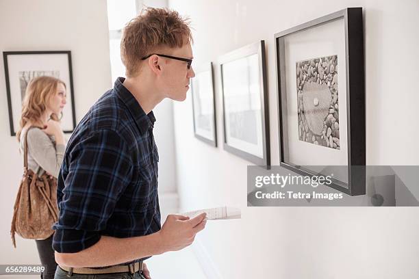 young couple looking at photographs at museum - couple art gallery stock pictures, royalty-free photos & images