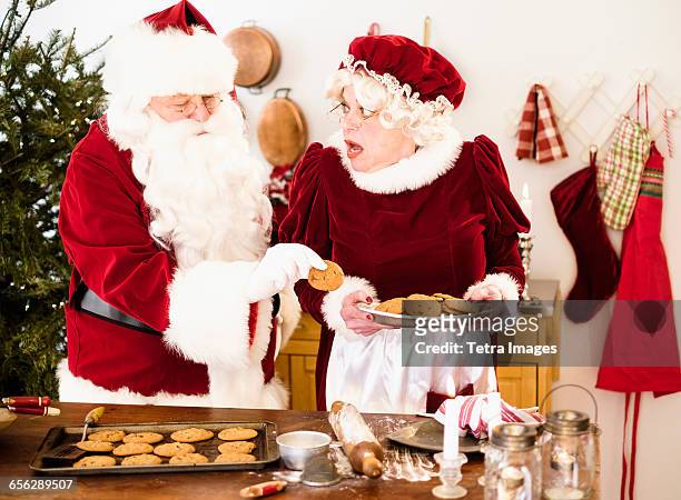santa stealing gingerbread cookie from mrs. claus - mrs claus stock pictures, royalty-free photos & images