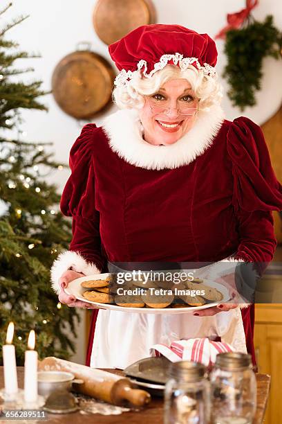 portrait of mrs. claus holding fresh gingerbread cookies - mãe natal imagens e fotografias de stock