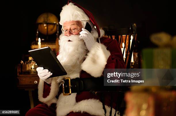 santa claus using digital tablet and talking by mobile phone - white glove stock pictures, royalty-free photos & images