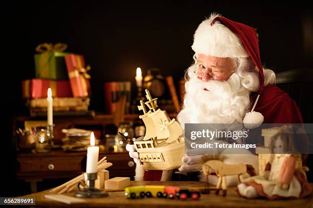 santa claus making wooden toy and winking - santas workshop stock pictures, royalty-free photos & images