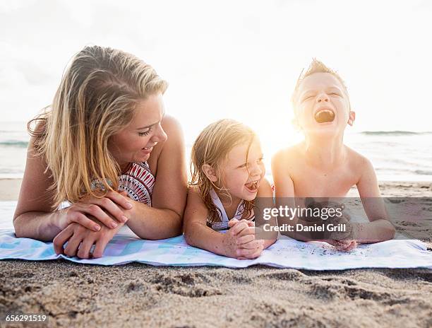 mother lying down with son (6-7) and daughter (4-5) on beach - beach florida family stockfoto's en -beelden