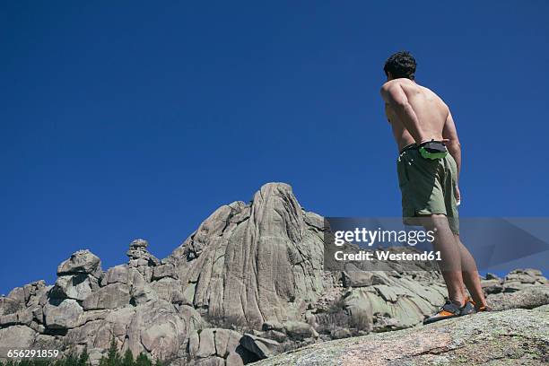 spain, shirtless climber using his chalk bag in front of the santillana's wall in la pedriza - chalk bag stock-fotos und bilder