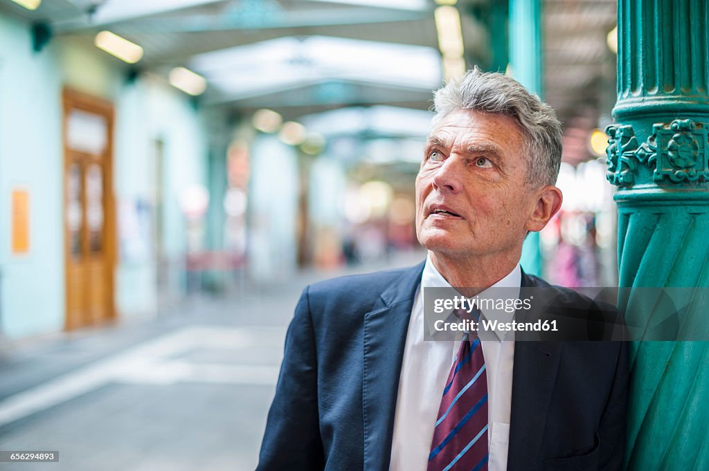 Senior businessman at column looking up