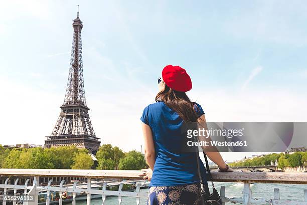 france, paris, back view of woman wearing red beret looking at eiffel tower - person eiffel tower stock pictures, royalty-free photos & images