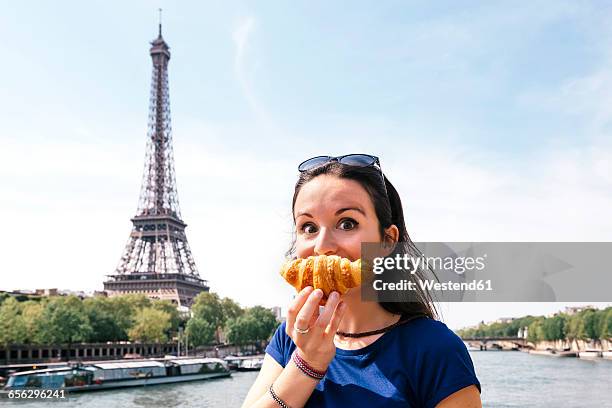 france, paris, staring woman with croissant in front of seine river and eiffel tower - paris france bildbanksfoton och bilder