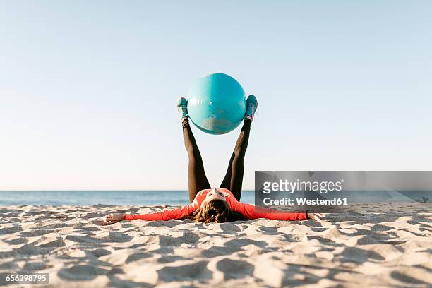 woman doing sports with gym ball early in the morning on the beach - yoga ball outside stock pictures, royalty-free photos & images