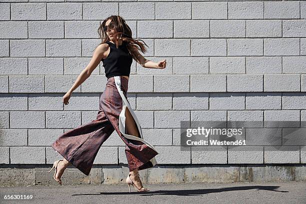 fashionable young woman passing brick wall - fashionable sunglasses stock pictures, royalty-free photos & images