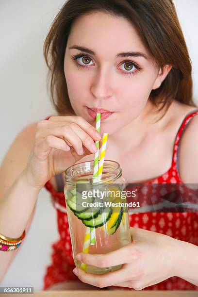 portrait of woman drinking detox water infused with lemon and cucumber - cucumber foto e immagini stock