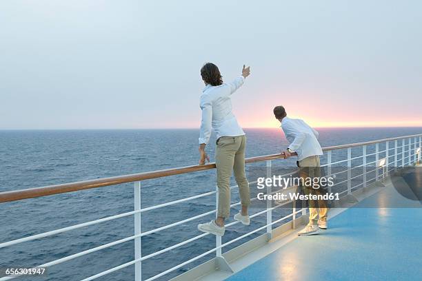 young men standing on deck of ship, watching sunset - cruise deck stock-fotos und bilder