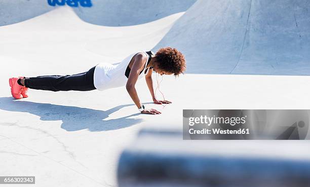 young woman doing pushups in skatepark - entrenamiento-sin-material fotografías e imágenes de stock