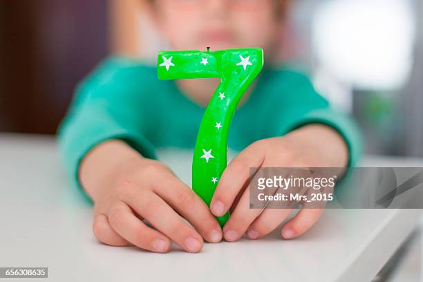 boy holding number seven birthday candle - 7th birthday stock pictures, royalty-free photos & images