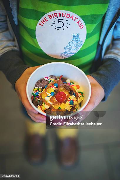 boy holding tub of frozen yogurt with sprinkles - yoghurt tub stock pictures, royalty-free photos & images