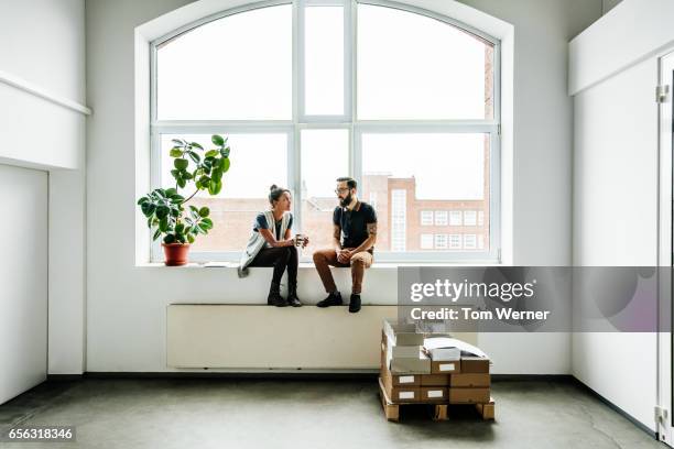 young start up business people sitting in a window and talking - big office fotografías e imágenes de stock