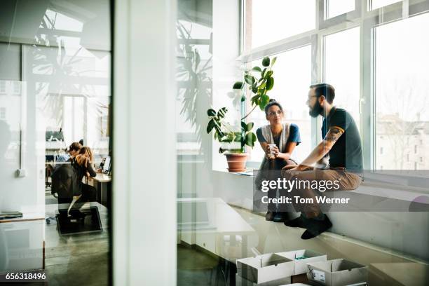 young start up business people sitting in a window and talking - durchsichtig kleidung frau stock-fotos und bilder