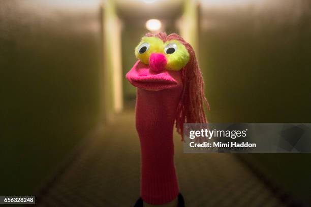 pink sock puppet with googly eyes in long corridor - fantoche imagens e fotografias de stock
